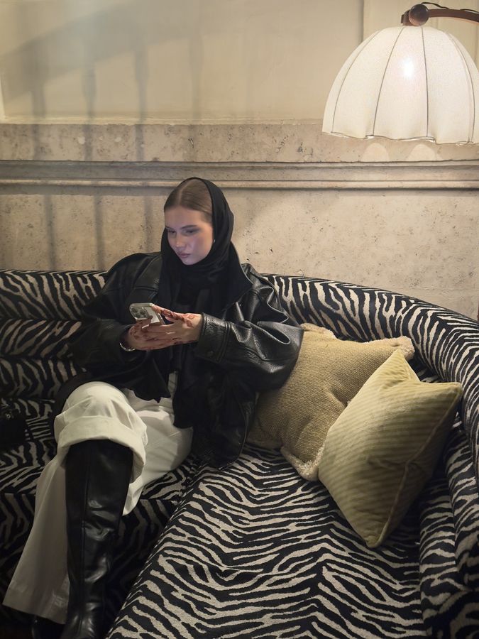 Kielo on a zebra-print sofa, looking at her phone